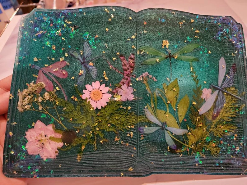 Whimsical hand crafted open book made out of resin.  There are some real leaves and flowers in the book!